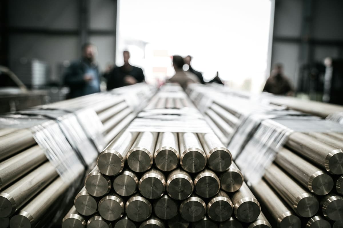 Buyers and suppliers inspecting bundles of steel bars in a production hall